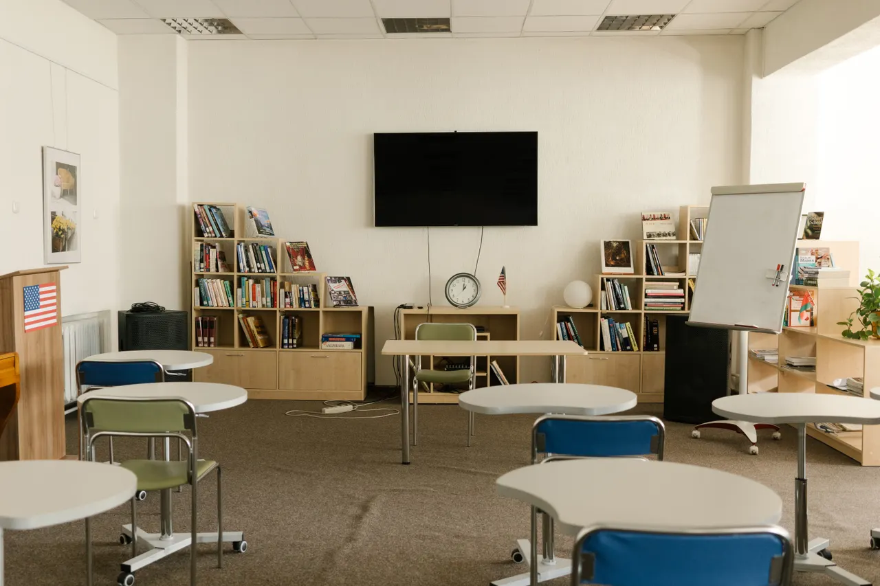 An empty classroom with bookshelves, desks and a whiteboard